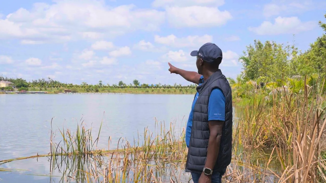 The FKLM Africa Foundation Founder points across a reservoir during a watershed field visit.